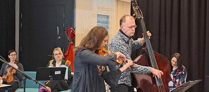 Sampo Lassila ja Krista Jäänsola esittämässä koulutuksen päätösseminaarissa viululla ja kontrabassolla esitystä ”Kohtaaminen potilashuoneessa”.