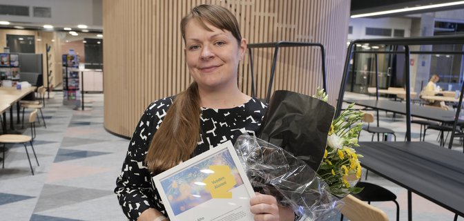 Vuoden alumni Niina Alho EDuCityssä kädessään kunniakirja ja palkintokukat.
