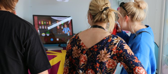 Kuvassa kolme henkilöä katsomassa tietokoneen näyttöä, jossa näkyy Mocktail Master peli.