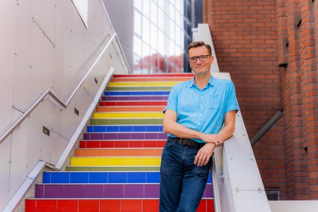 Turun AMK:n rehtori Vesa Taatila seisoo hymyillen sateenkaaren värein maalatuilla portailla.