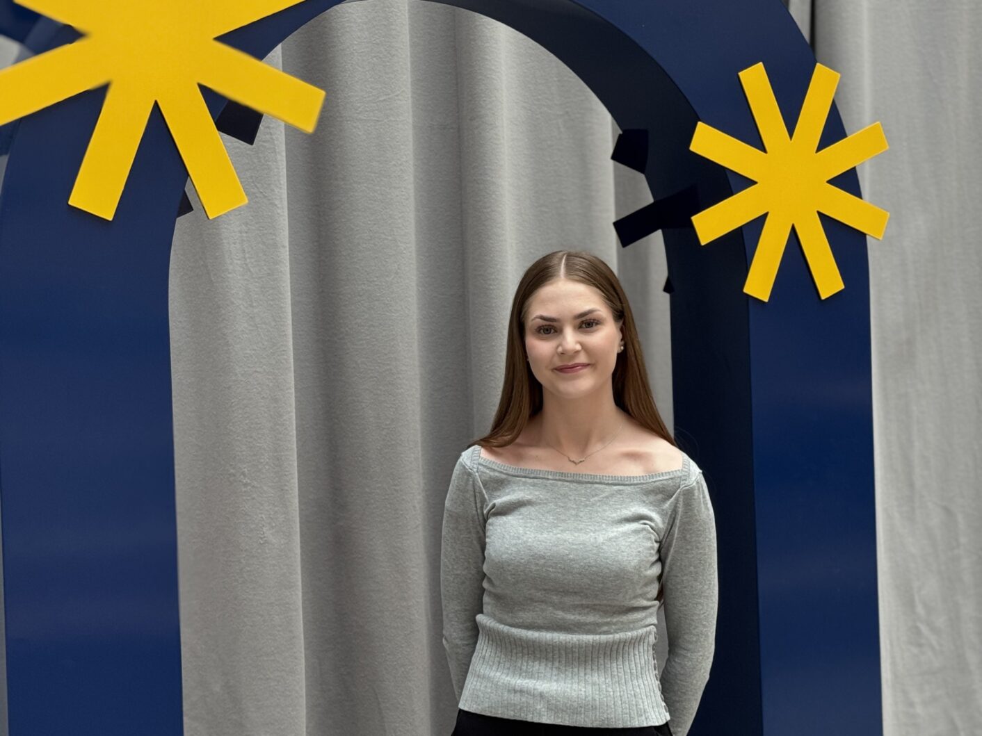 Kuvassa henkilö seisoo Turun AMK:n sinisen valokuvauskaaren alla.