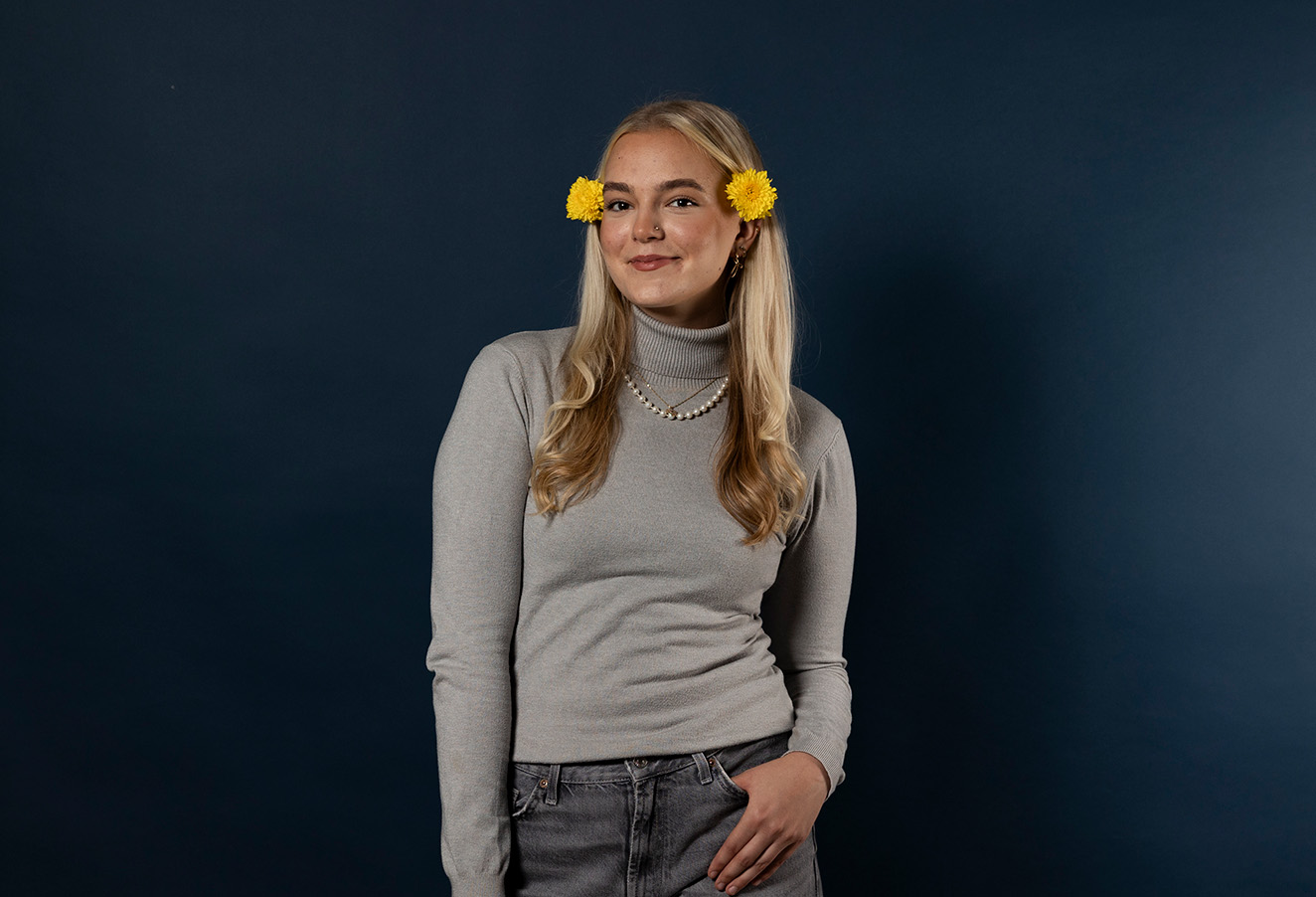 Henkilö katsoo kameraan tummansinisen taustan edessä.