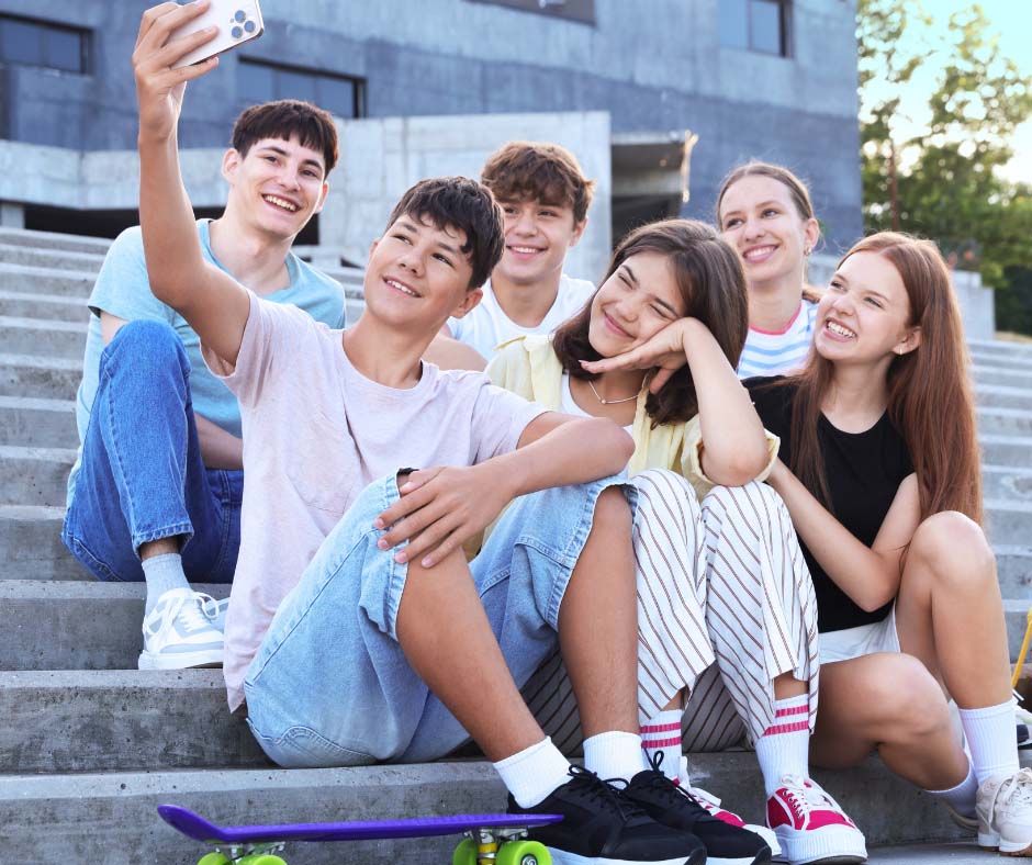 Iloisia nuoria istuu ulkona portailla ottamassa selfietä