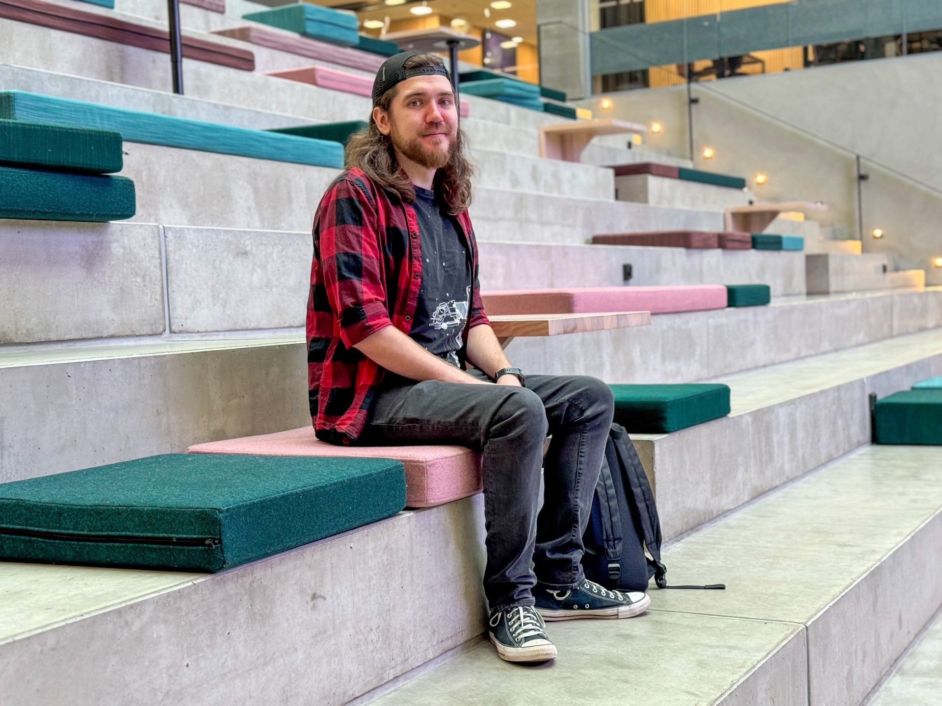 Henkilö istuu betonisilla portailla värikkään istuintyynyn päällä.