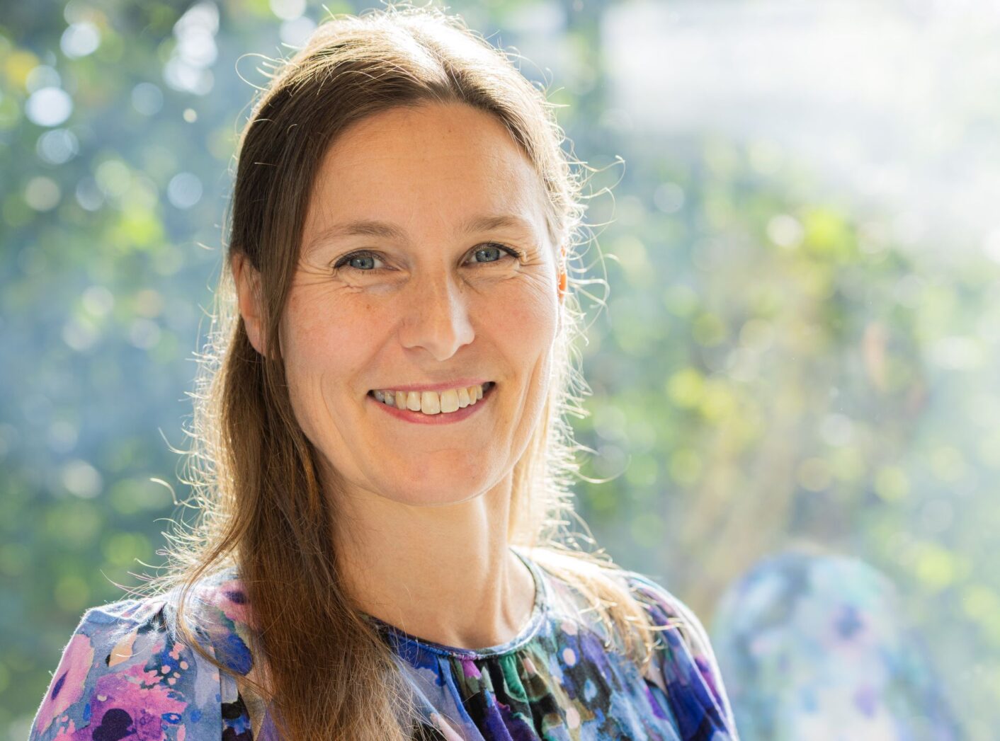 Anna Jussilainen lähikuvassa, taustalla vihreitä kasveja