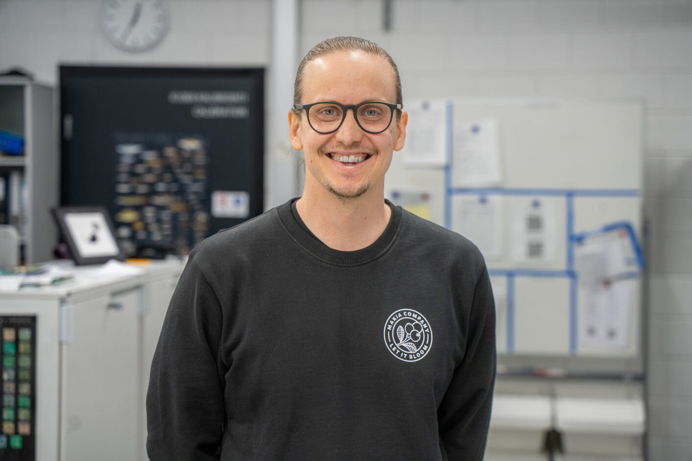 Mustaan paitaan pukeutunut mies seisoo kameran edessä.