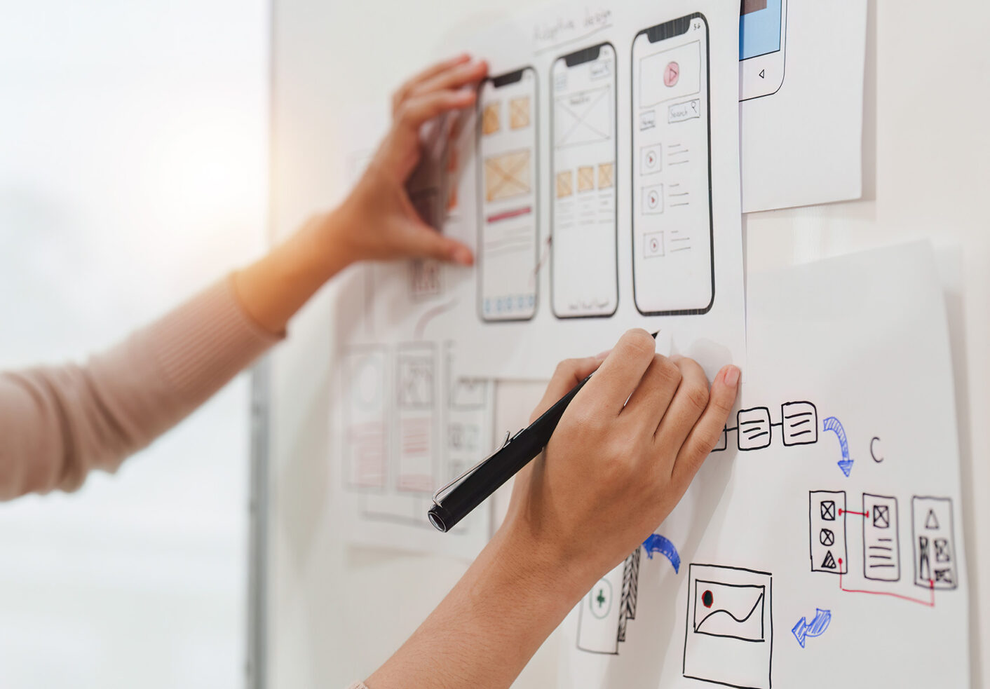 Henkilö kirjoittaa seinälle ideapapereihin