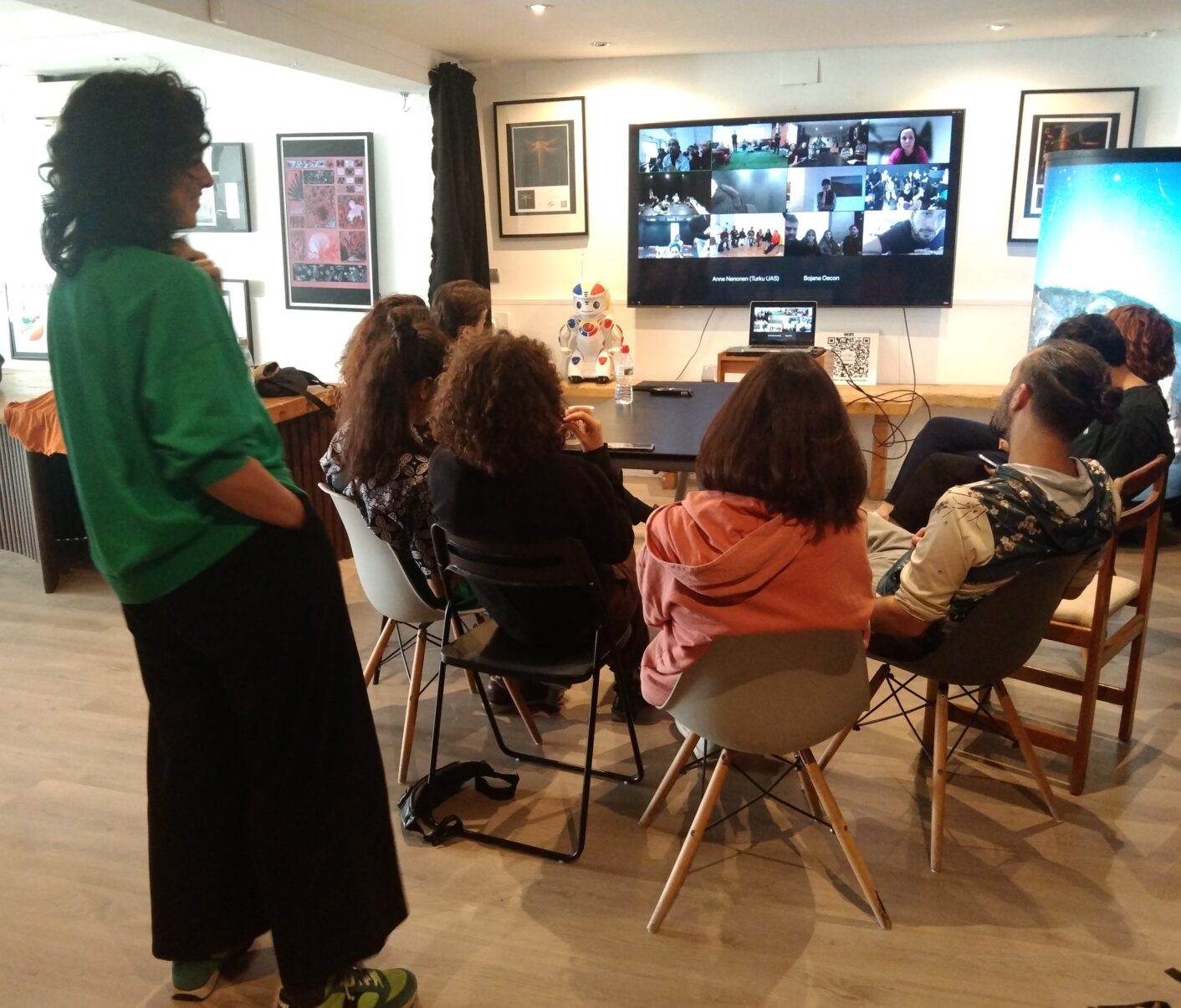 henkilöitä pöydän ääressä osallistumassa etätapaamiseen