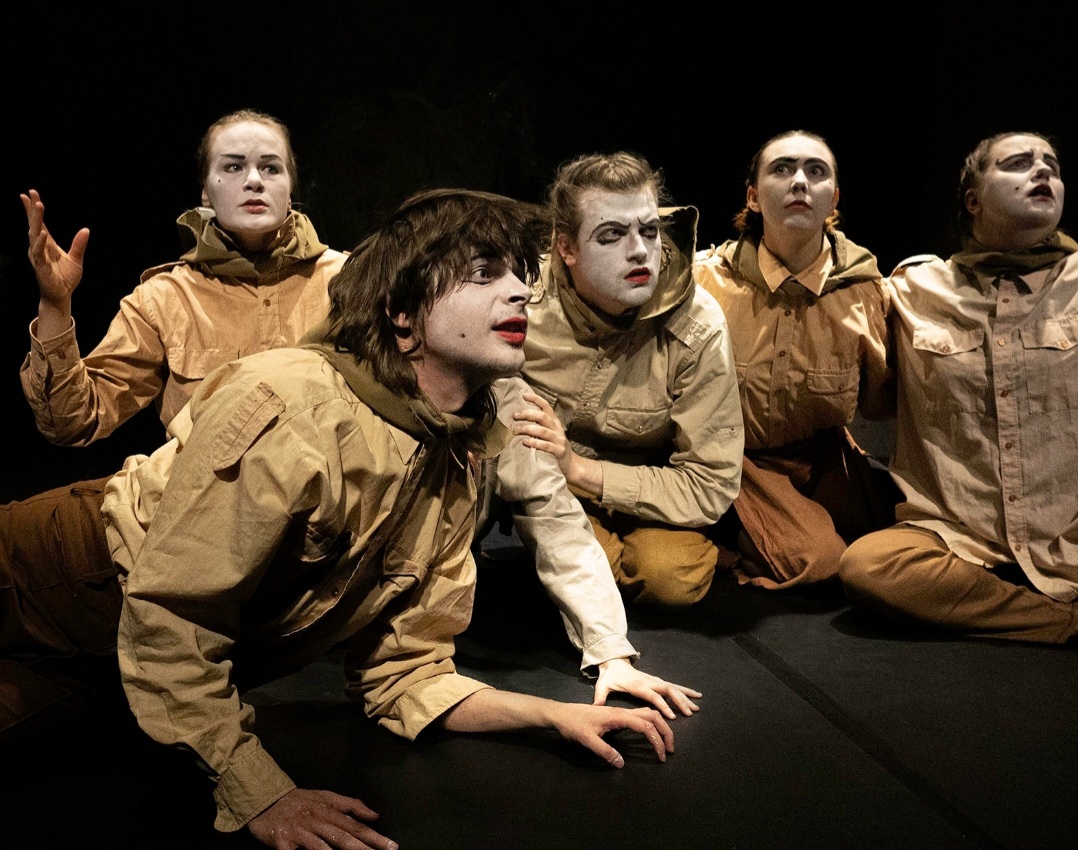 valkopukuisia ja -kasvoisia näyttelijöitä lavalla ryhmässä