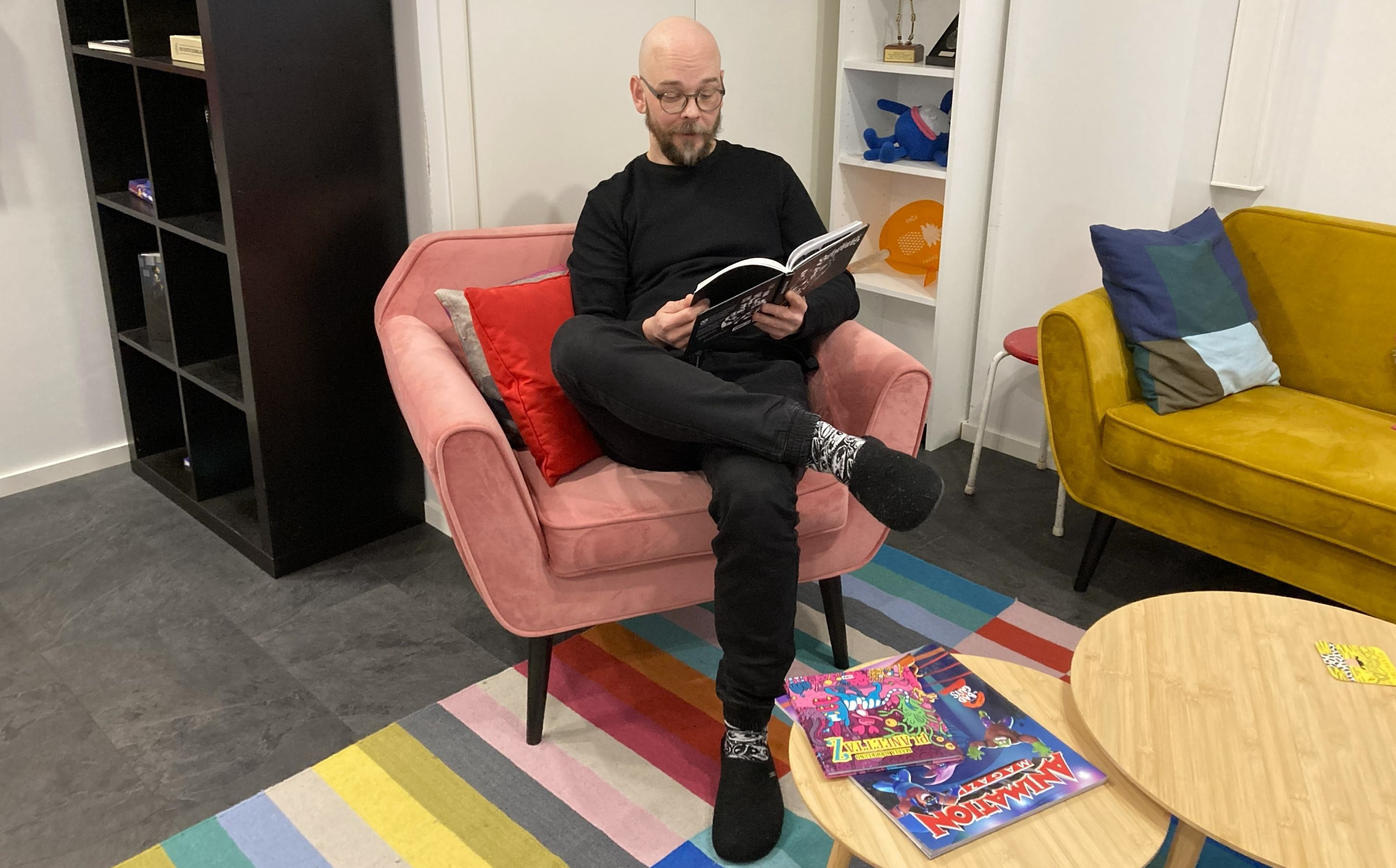 henkilö istuu nojatuolissa ja lukee sarjakuvakirjaa