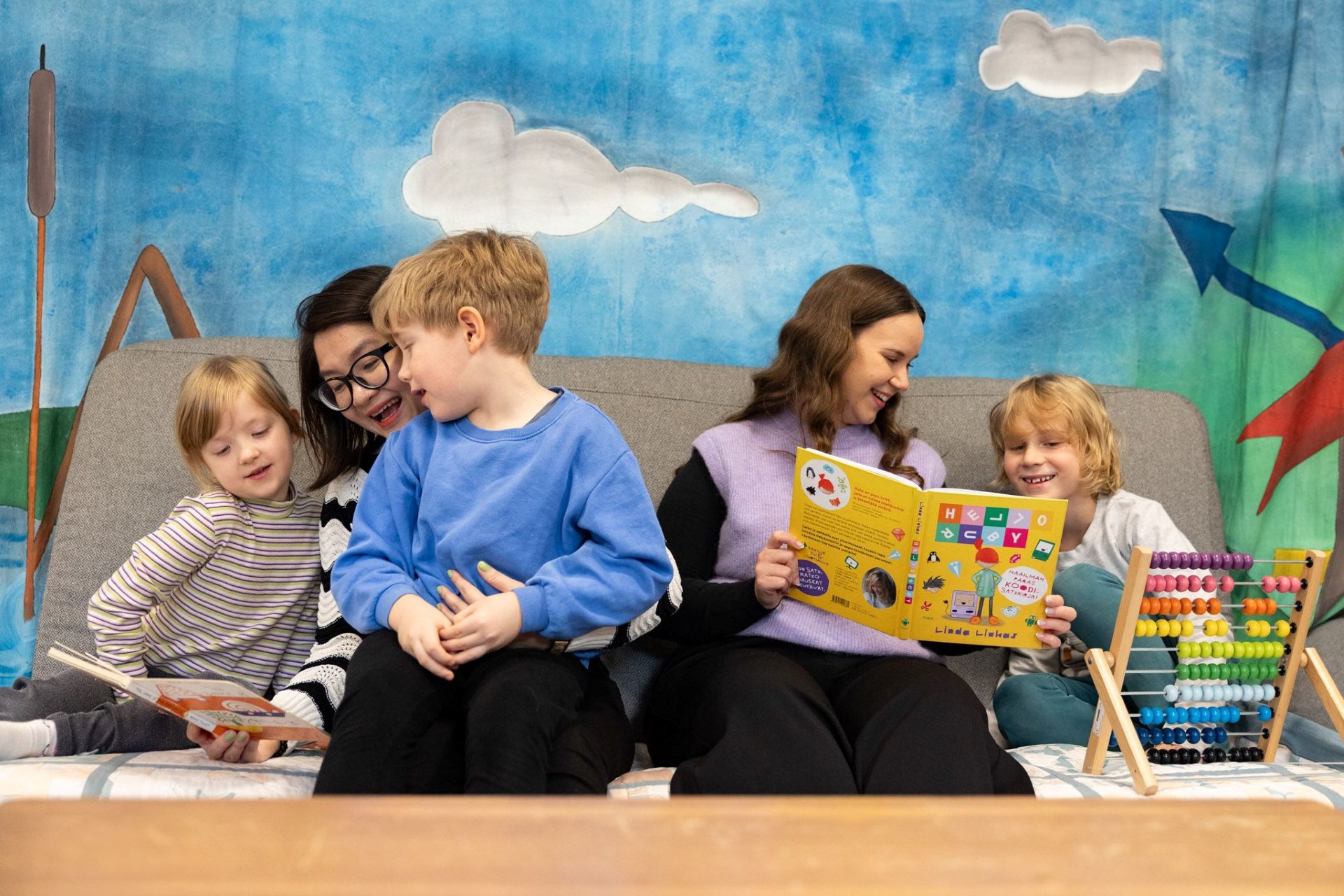 Lapset lukevat kirjaa yhdessä aikuisten kanssa.