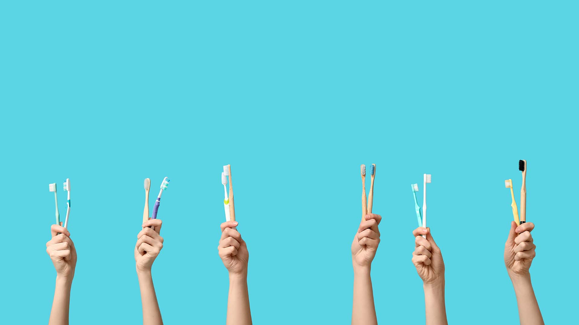 Turkoosilla taustalla 6 kättä pystyssä ja kaikissa käsissä 2 hammasharjaa