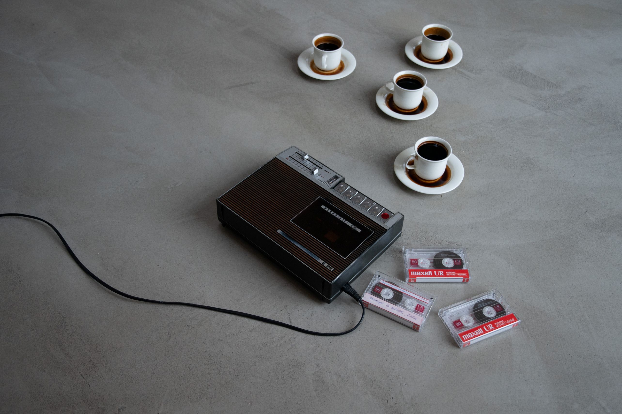 Kuva Minea Lehtisen performanssista. Kuvassa neljä kahvikuppia, kasetteja ja kasettisoitin